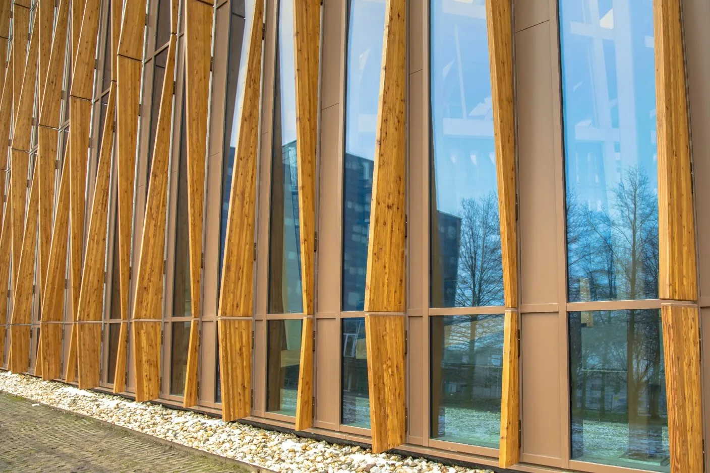 Eine moderne Fassade mit großen Glasfenstern und vertikalen Holzelementen.