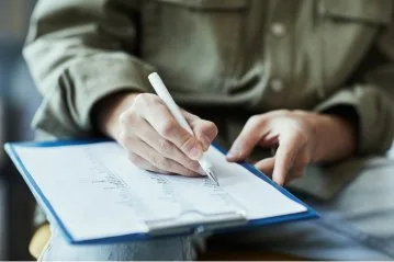 Eine Person schreibt auf einem Klemmbrett.